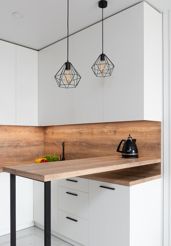 Interior of modern white kitchen with timber table and metal geometrical glowing lamps